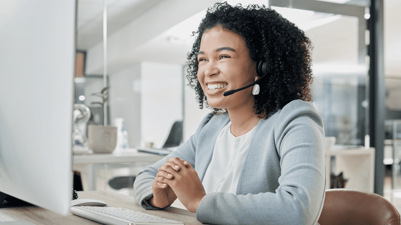 Smiling woman in headset working at a computer in a modern office
